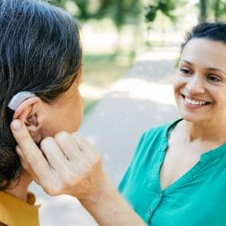 Woman with hearing aid chatting with her friend outdoors.
