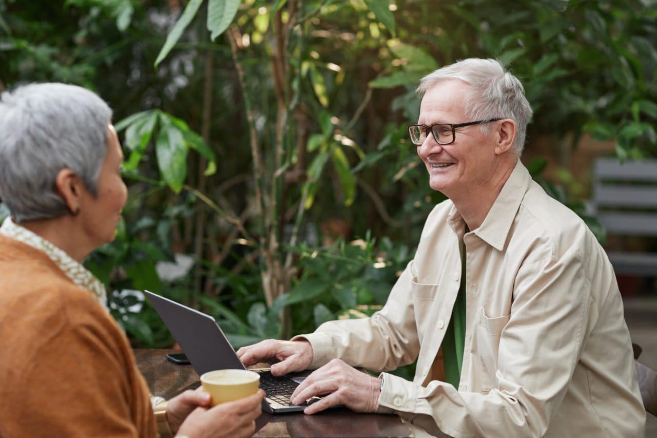 Older couple enjoying coffee at an outdoor cafe.