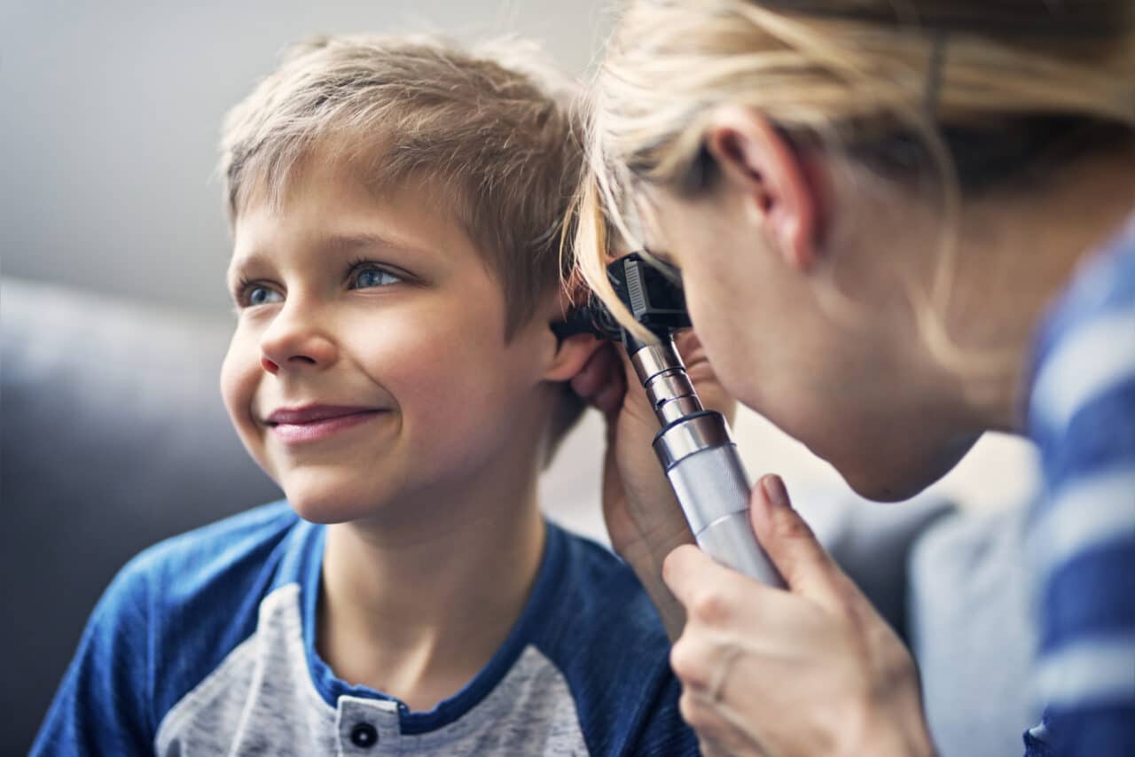 Little boy having his ear examined by a medical professional.