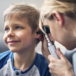 Little boy having his ear examined by a medical professional.