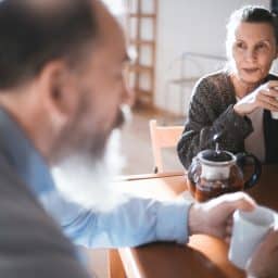 Woman looking at her husband as they're drinking their morning coffee.