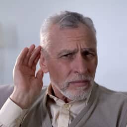 Senior man looking confused with a hand up to his ear