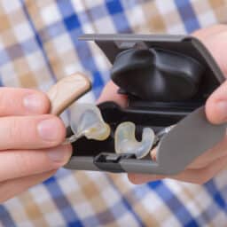 Close-up of a man holding hearing aids in their case
