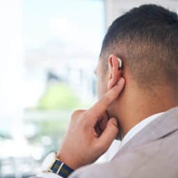 Rear view of a man pointing to his hearing aid