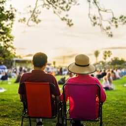 Couple sitting on the picnic chairs, listening to the music concert.