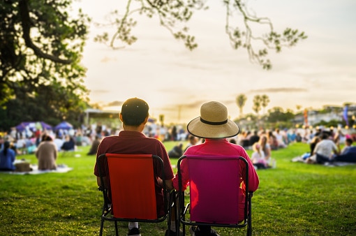 Couple sitting on the picnic chairs, listening to the music concert. 