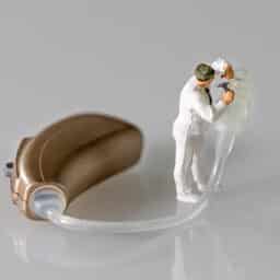 Miniature figurine audiologist adapting hearing aid.