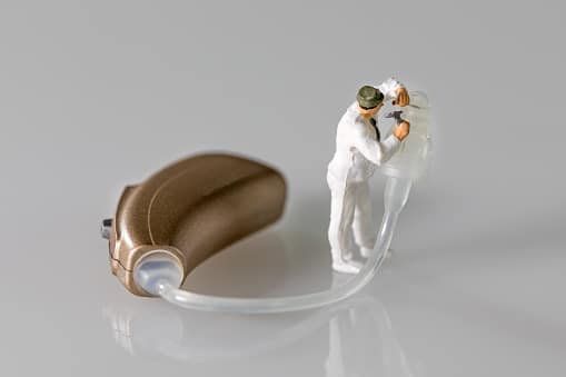 Miniature figurine audiologist adapting hearing aid